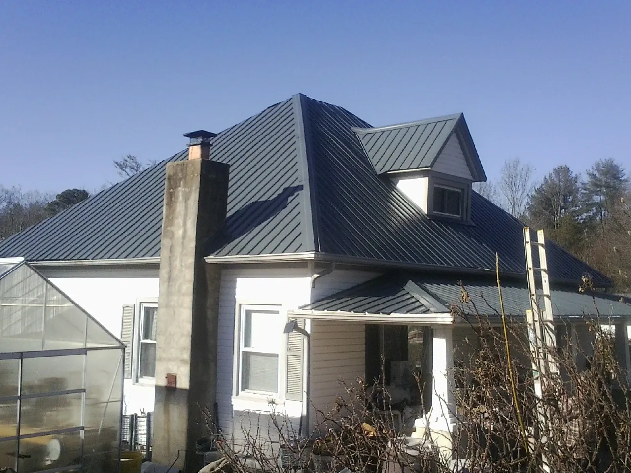 Dark blue standing seam metal roof on a white farmhouse with dormer — Slate & Tile Roof Repair by Roofing Brothers in Newfields