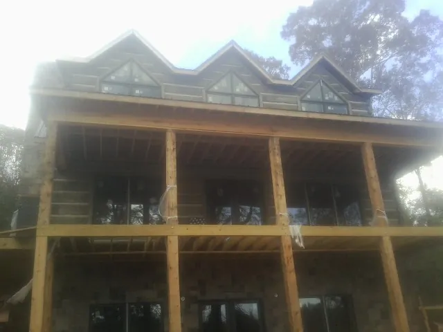 Dormers and porch framing on a large log home under construction — Roof Coating work by our crew in Newfields