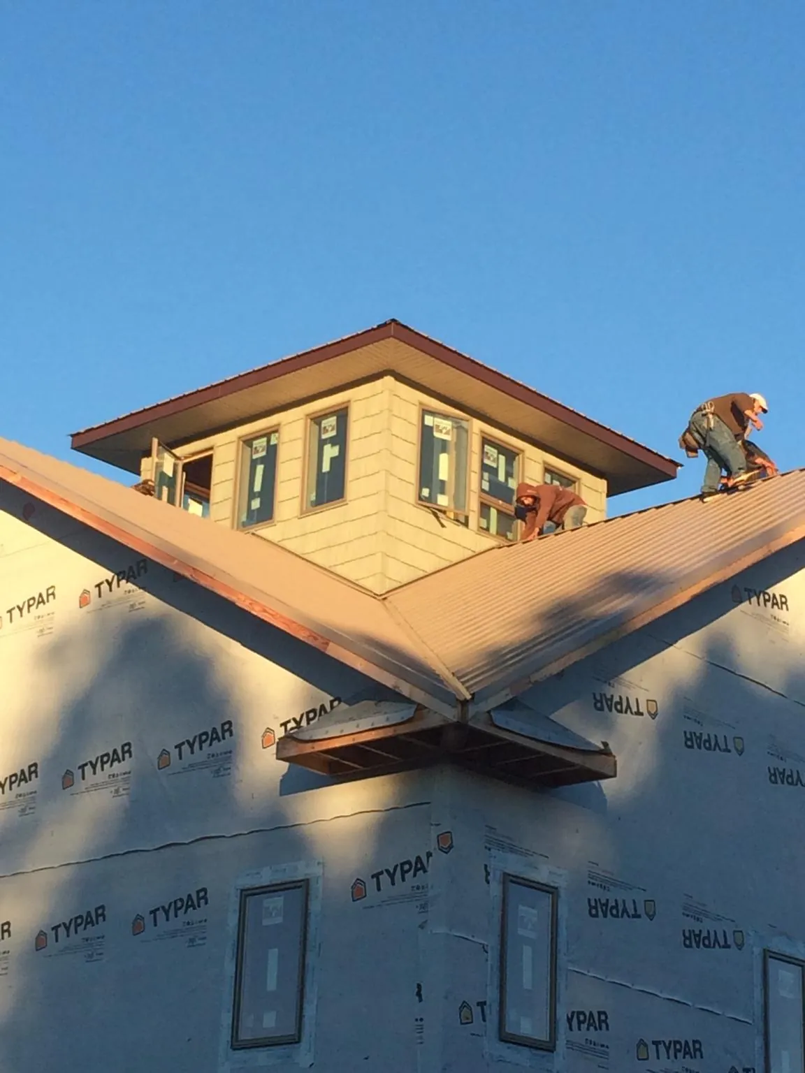 Roofers working around a rooftop cupola on a new metal roof at sunset — Roof Waterproofing in Newfields by Roofing Brothers